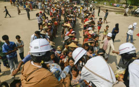 People line up for food aid being distributed in Sagaing, Myanmar on 3 April, 2025, following the 28 March earthquake.