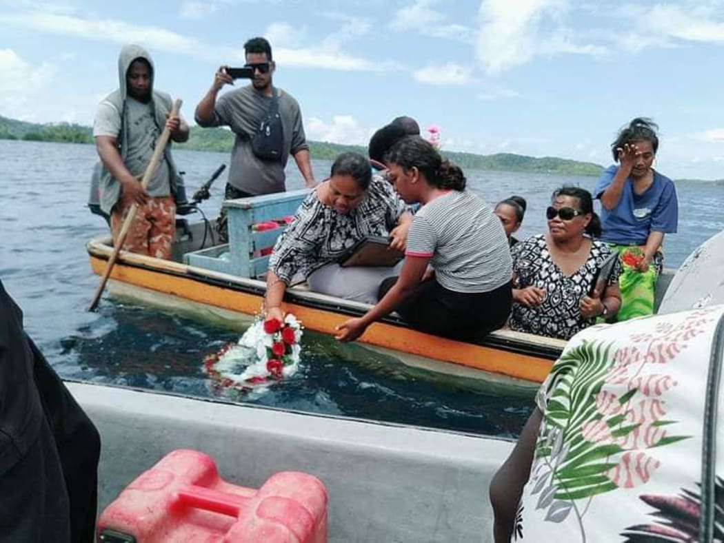 A family lays a wreath during the memorial service for the 14 people missing at sea.