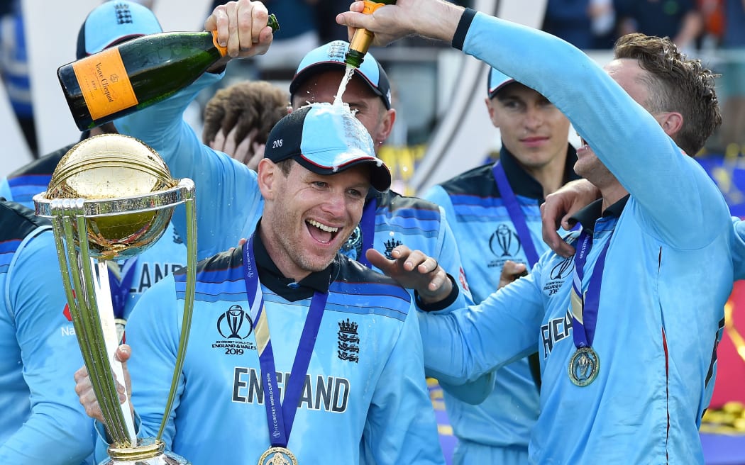 England's captain Eoin Morgan is covered in champagne as he poses with the World Cup trophy as England's players celebrate their win after the 2019 Cricket World Cup final between England and New Zealand at Lord's Cricket Ground in London on July 14, 2019.