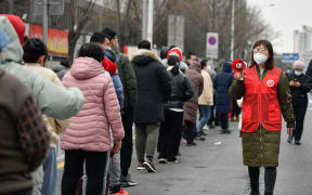 A volunteer gives citizens tips on nucleic acid test at a testing site in Nankai District, north China's Tianjin.