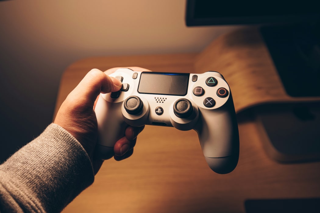 Person's hand on the arrow keys of a PlayStation controller.