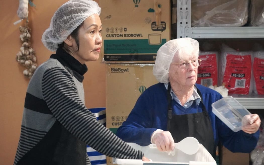 Volunteers Sombath Samountry, left, and Evelyn Clibborn packing meals.