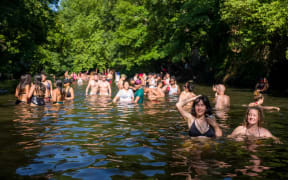 Sun-seekers cool off in the water and sunbathe on the riverbank at Hackney Marshes in east London on June 24, 2020, as temperatures reached 31 degrees.
