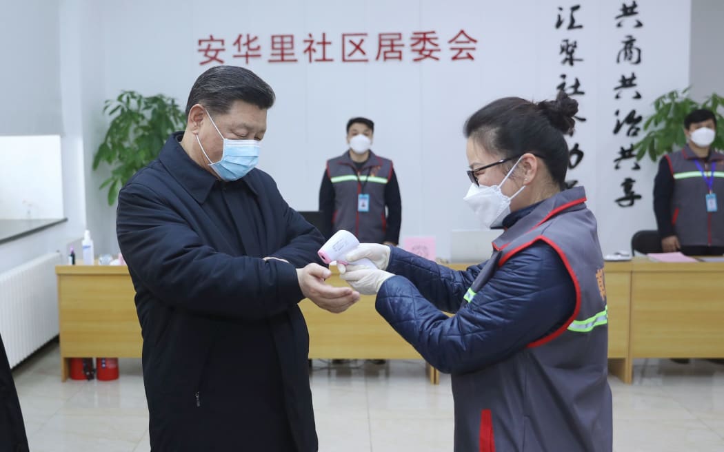 Chinese President Xi Jinping wearing a protective facemask as a health official checks his body temperature during an inspection of the novel coronavirus pneumonia prevention and control work at the Anhuali Community in Beijing.