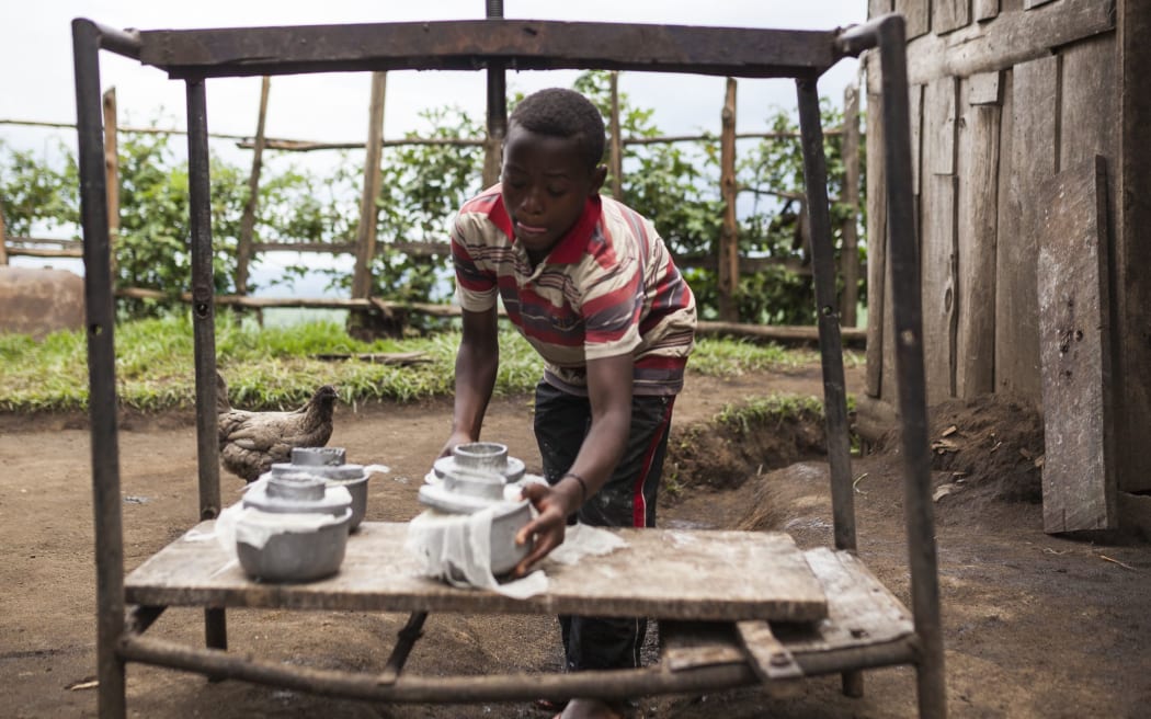 A boy working at a cheese factory organises moulds containing fresh cheese in Kilolirwe in the eastern territory of Masisi, DRC.