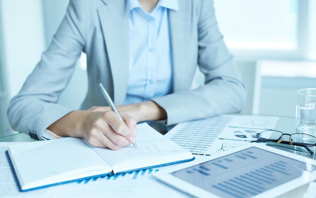 Image of businesswoman writing in notepad at workplace