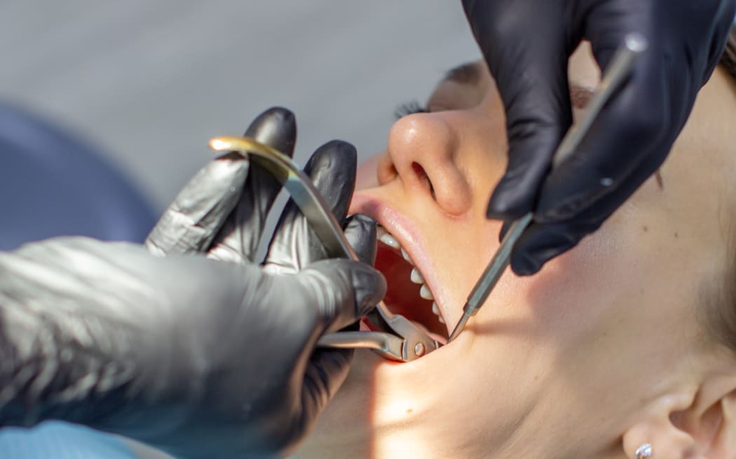Beautiful woman in dental chair during procedure of installing braces to upper and lower teeth. Dentist and assistant working together, dental tools in their hands. Top view. Concept of dentistry