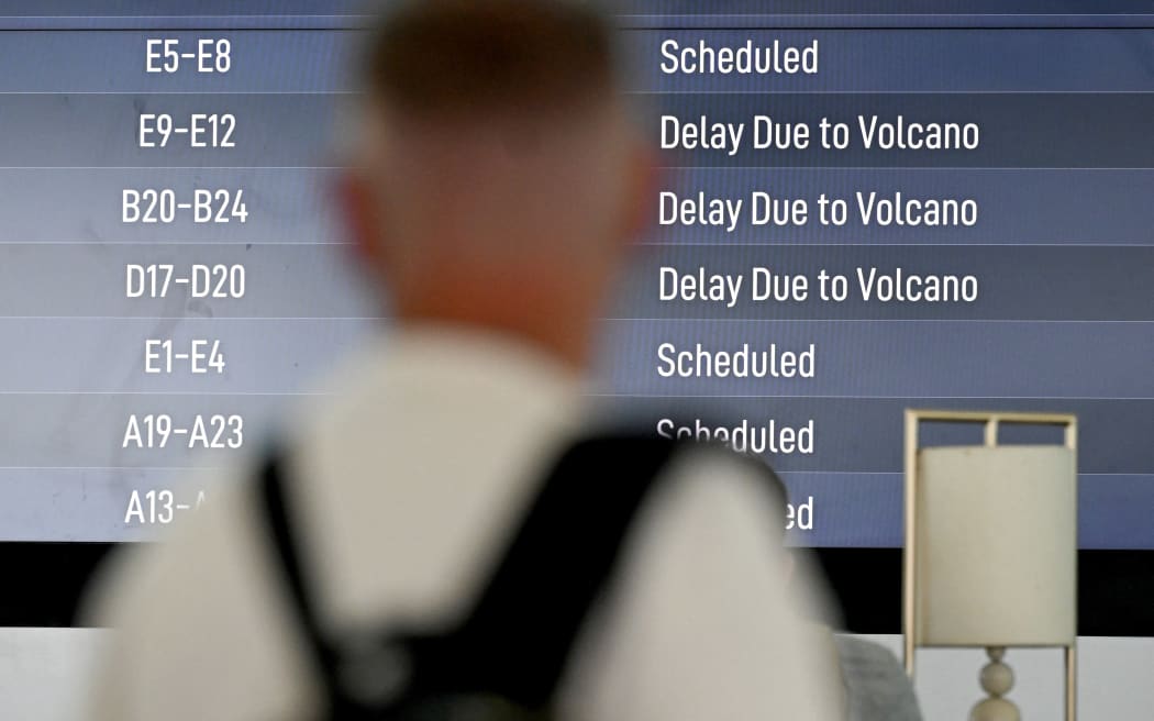 Passengers look at an electronic board displaying cancelled flights at the Ngurah Rai International Airport in Tuban near Denpasar on Indonesia's resort island of Bali on March 21, 2025, after Mount Lewotobi Laki-Laki volcano in the archipelago nation's east erupted, shooting dark ash eight kilometres into the sky. (Photo by SONNY TUMBELAKA / AFP)