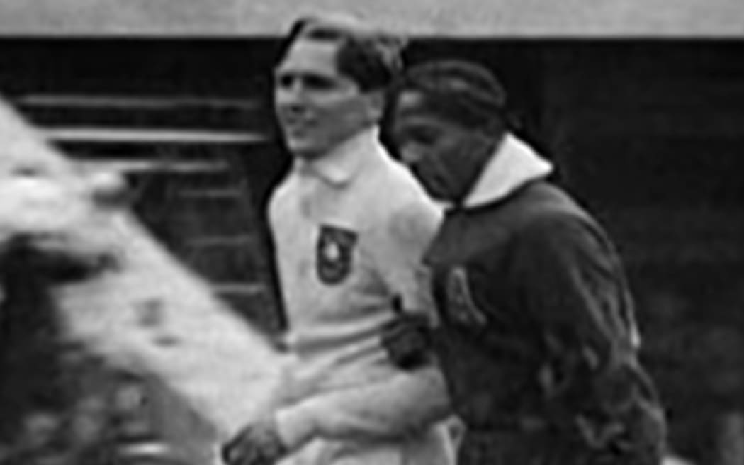 Jesse Owens and Luz Long walk arm-in-arm around the track and field stadium at the 1936 Summer Olympics in Berlin.