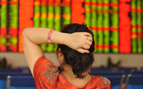 A concerned Chinese investor looks at prices of shares (red for price rising and green for price falling) at a stock brokerage house in Fuyang city, east China's Anhui province, 24 June 2016.