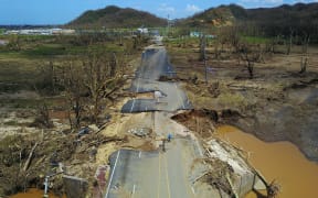 A man rides his bicycle through a damaged road in Toa Alta, west of San Juan, Puerto Rico, on September 24, 2017 following the passage of Hurricane Maria.