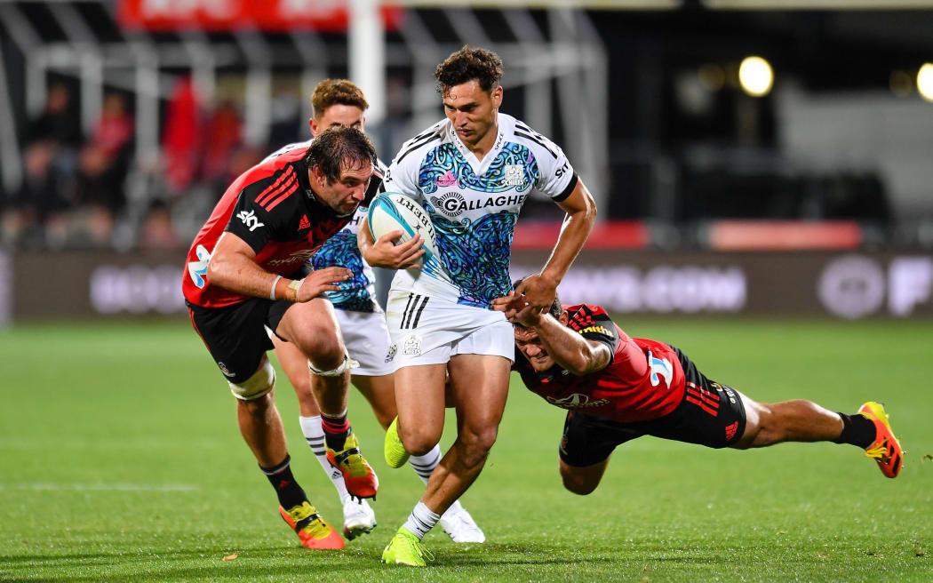 Shaun Stevenson of the Chiefs eludes Codie Taylor and Sam Whitelock of the Crusaders during the Super Rugby Pacific match, Crusaders Vs Chiefs, at Orangetheory Stadium, Christchurch, New Zealand, 12 March 2022.