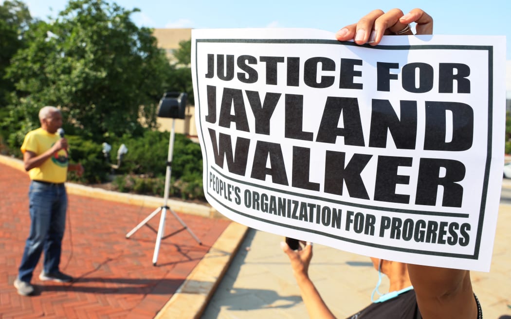 NEWARK, NEW JERSEY - JULY 15: A person holds a sign as people gather for a rally demanding justice for Jayland Walker on at Essex County Historic Courthouse on July 15, 2022 in Newark, New Jersey. The People’s Organization for Progress (POP) organized a march and rally to demand justice for Jayland Walker, who was killed in Akron, Ohio by police on June 27, 2022. According to a medical examiner's report released today Walker, who was unarmed at the time, suffered 46 gunshot wounds after multiple police officers shot at him an estimated 90 times following a car chase. The family held an open casket funeral for Walker on July 13th, and drew comparisons to a choice by Emmett Till’s mother 67 years ago that helped galvanize the national Civil Rights Movement.   Michael M. Santiago/Getty Images/AFP (Photo by Michael M. Santiago / GETTY IMAGES NORTH AMERICA / Getty Images via AFP)