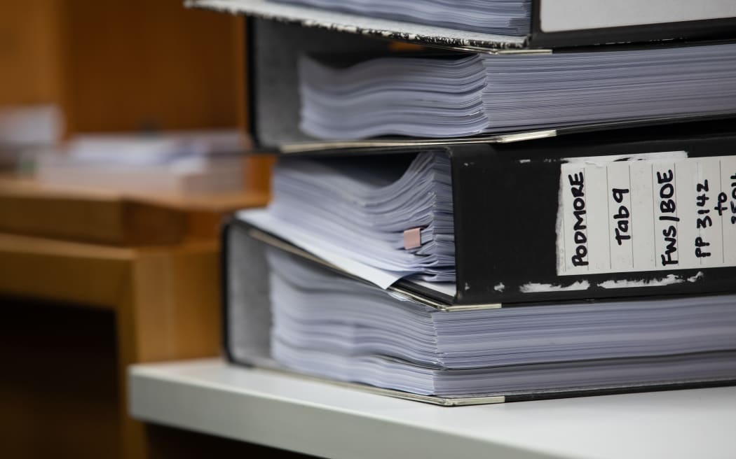 A folder sits on a bench in the courtroom with the word PODMORE on the spine on day one of the coroner's inquest.