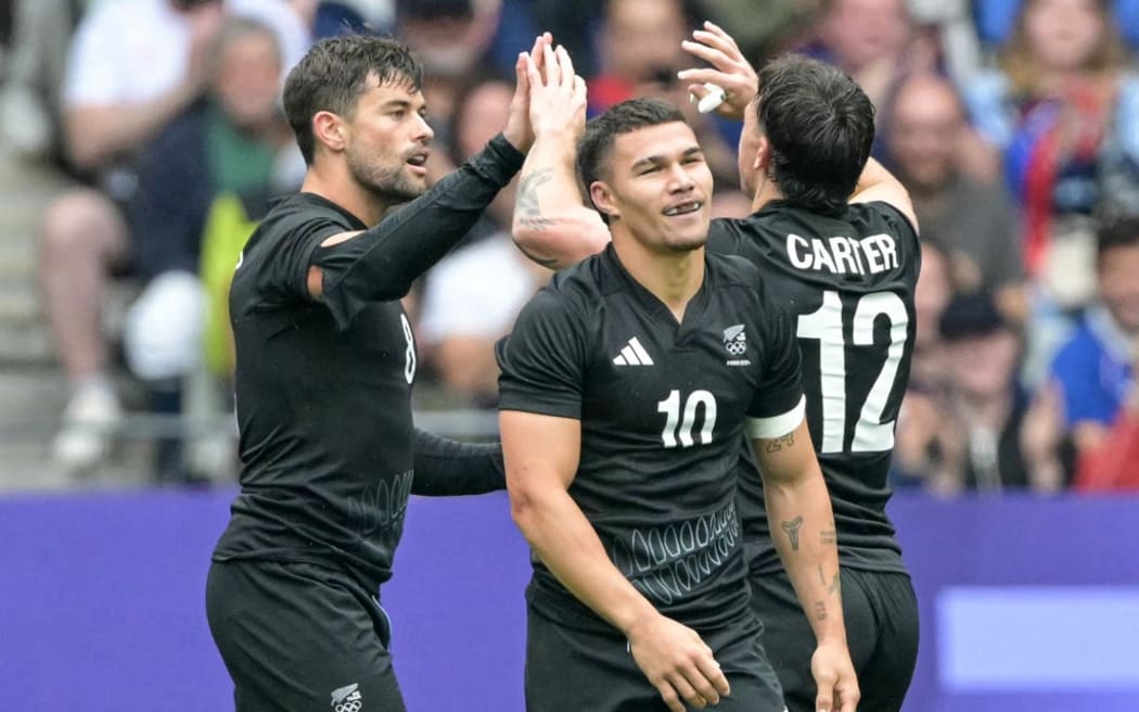 (From L) New Zealand's Andrew Knewstubb, New Zealand's Tepaea Cook-Savage and New Zealand's Leroy Carter celebrate after a try during the men's placing 5-8 rugby sevens match between New-Zealand and Argentina during the Paris 2024 Olympic Games at the Stade de France in Saint-Denis on July 27, 2024. (Photo by CARL DE SOUZA / AFP)