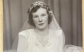 A photo of a young bride, holding a bouquet of flowers, with the words 'Titchmarsh Studio, Auckland' written in the corner.