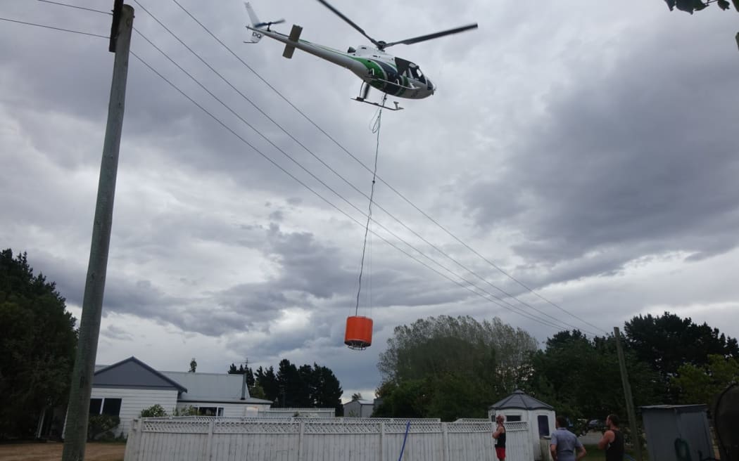 A helicopter fills monsoon bucket from a swimming pool.