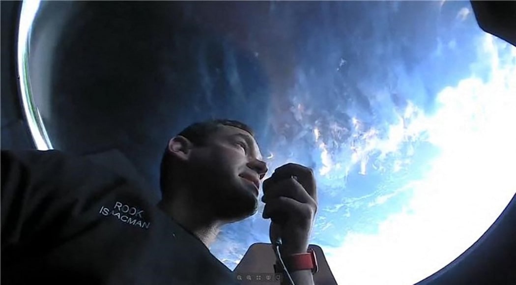 This September 16, 2021, image courtesy of Inspiration4 shows the Inspiration4 crew member Jared Isaacman communicating while looking out of an observation window while in orbit.