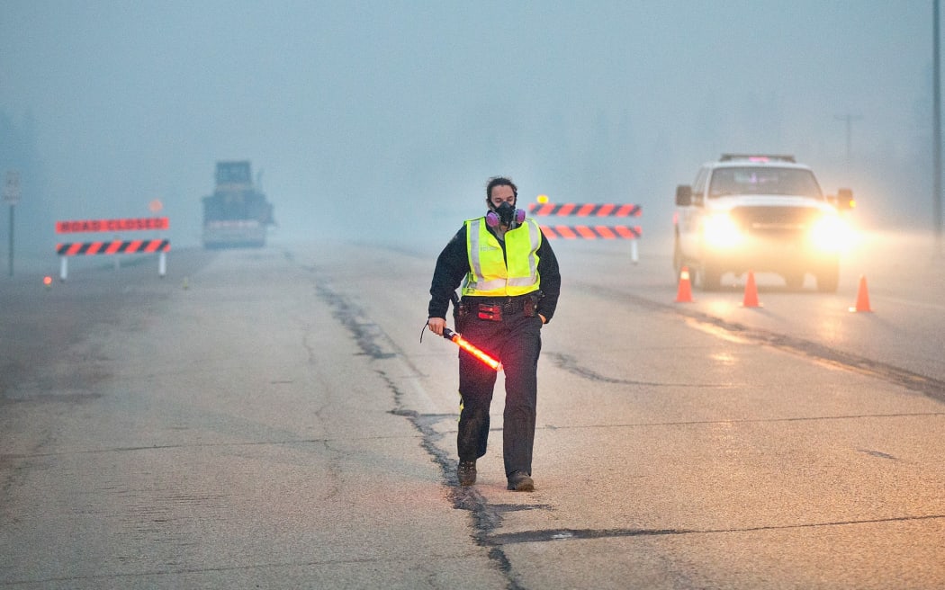 Smoke fills the air as a police officer stands guard at a roadblock along Highway 63 leading into Fort McMurray on May 8, 2016 near Fort McMurray, Alberta, Canada.