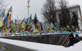 Pedestrians walk down stairs leading to an underground passage at the Memorial for the Fallen Ukrainian and Foreign Fighters on the Independence Square in Kyiv on December 26, 2025, amid the Russian invasion of Ukraine. (Photo by Tetiana DZHAFAROVA / AFP)
