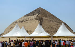 People gather during an inaugural ceremony in front of the Bent pyramid of King Sneferu, the first pharaoh of Egypt's 4th dynasty, in the ancient royal necropolis of Dahshur  south of  Cairo on July 13, 2019.
