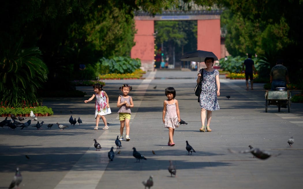 China to allow couples to have three children in major policy shift.
A group of Chinese children prepare to feed pigeons at a park in Beijing on August 7, 2014.