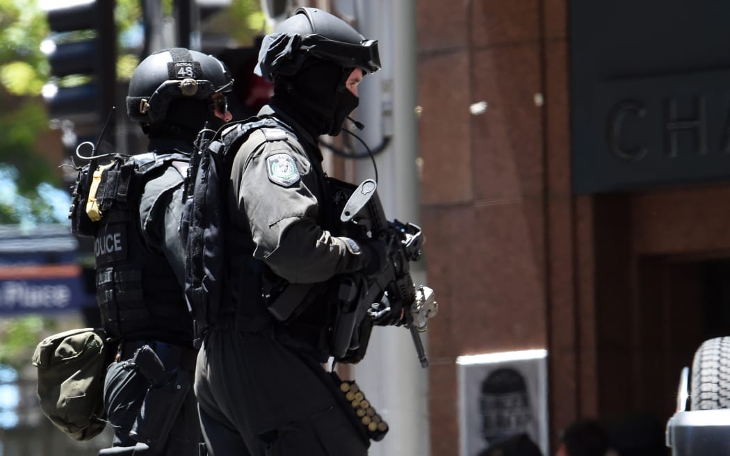 Armed police run toward a cafe in the central business district of Sydney