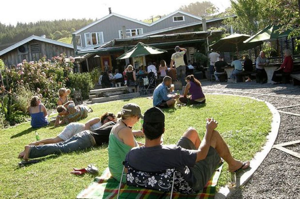 The Leigh Sawmill Cafe front lawn with people sitting in the sun.