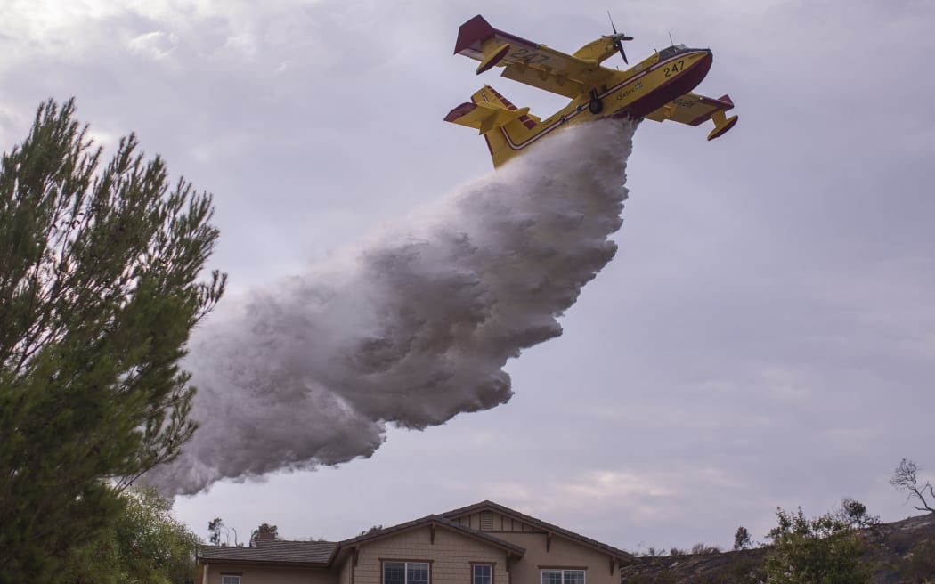 A Super Scooper CL-415 firefighting aircraft makes a drop to protect a house during the La Tuna Fire near Burbank, California.