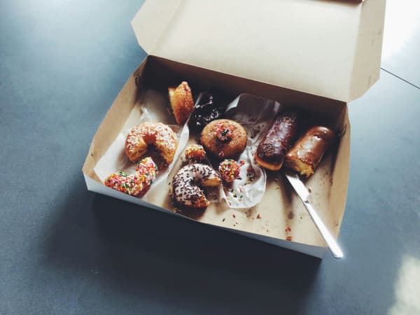 A carton box of half eaten pastries, including doughnuts.