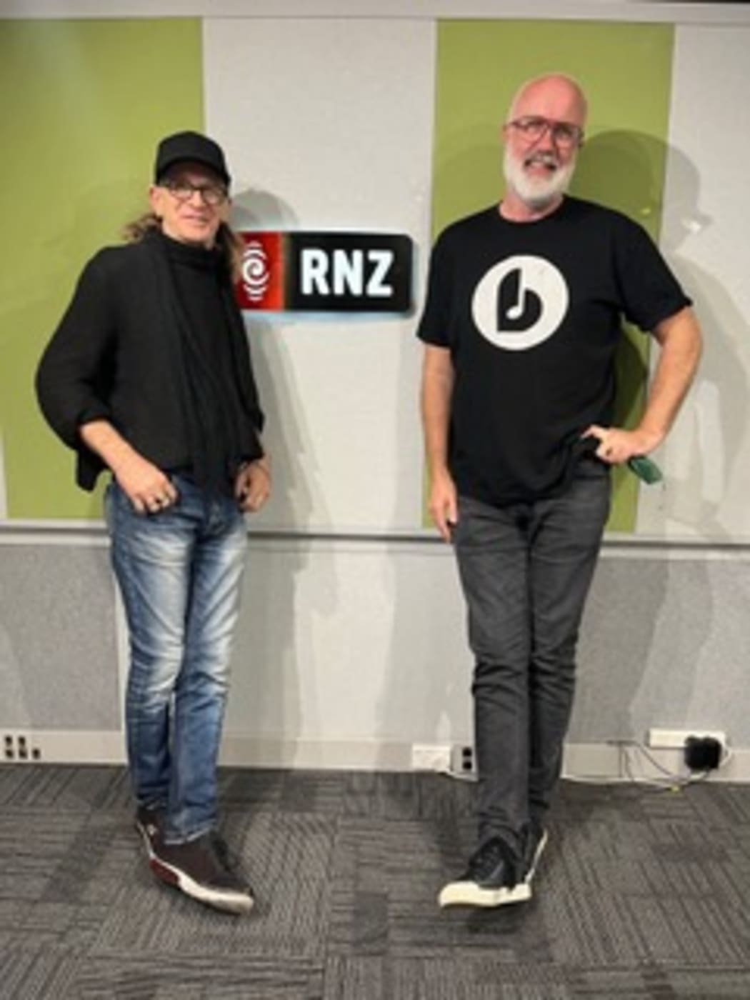 Trevor Reekie and Joost Langeveld pose in front of the RNZ sign at RNZ Auckland