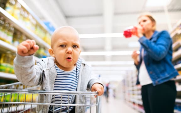 Unrecognizable young mother with her little baby boy at the supermarket, shopping.