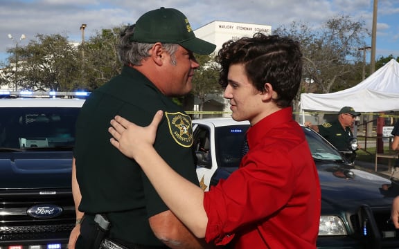 Alfonso Calderon, left, speaks with Broward County Sheriff officer Brad Griesinger as he guards the front gate of the school.