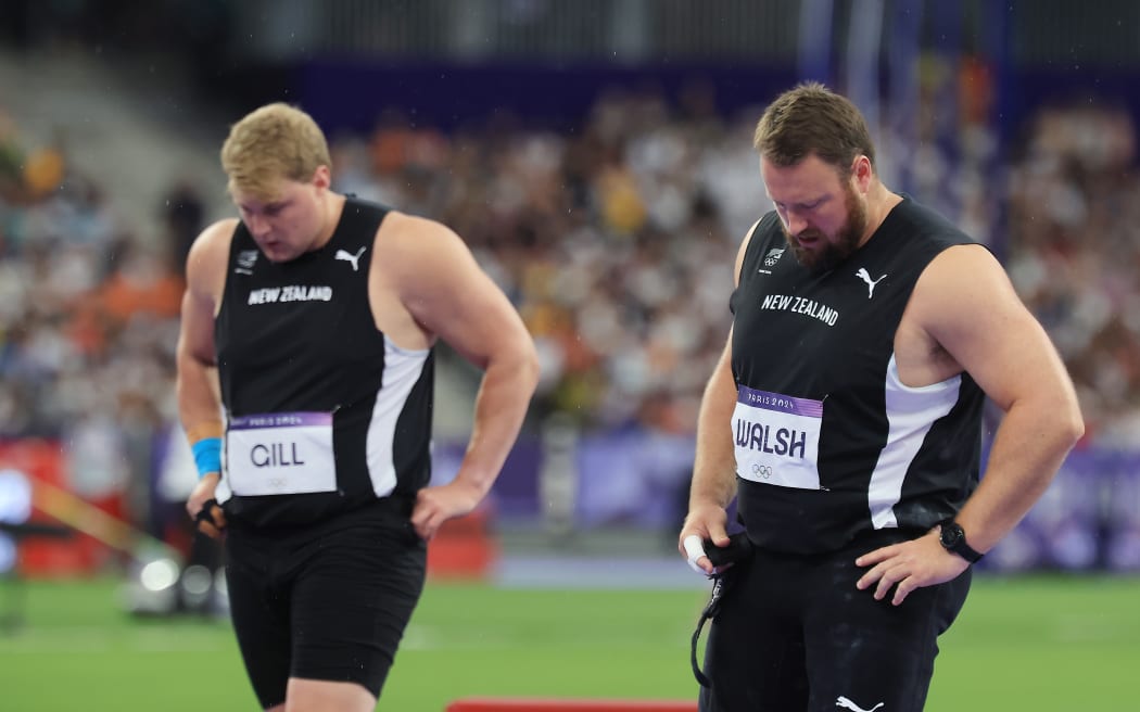 Jacko Gill and Tom Walsh wearing Team NZ uniform with heads bowed.