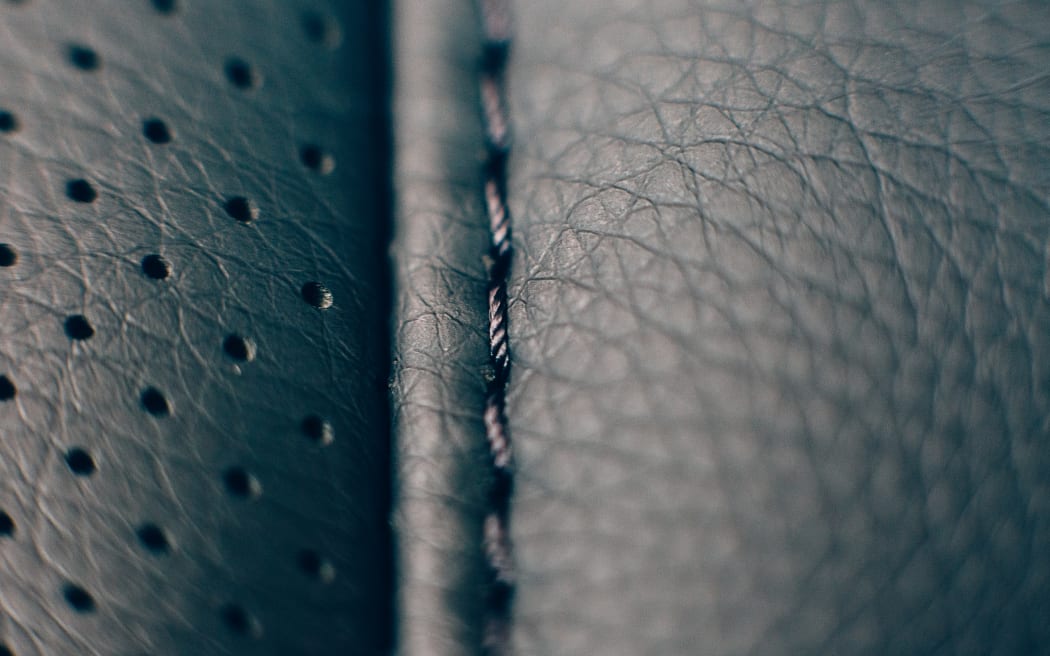 Close up of a detail of the stitches of a car seat in a black handmade leather upholstery.