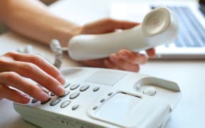 A person dials a number on a home landline phone (file)