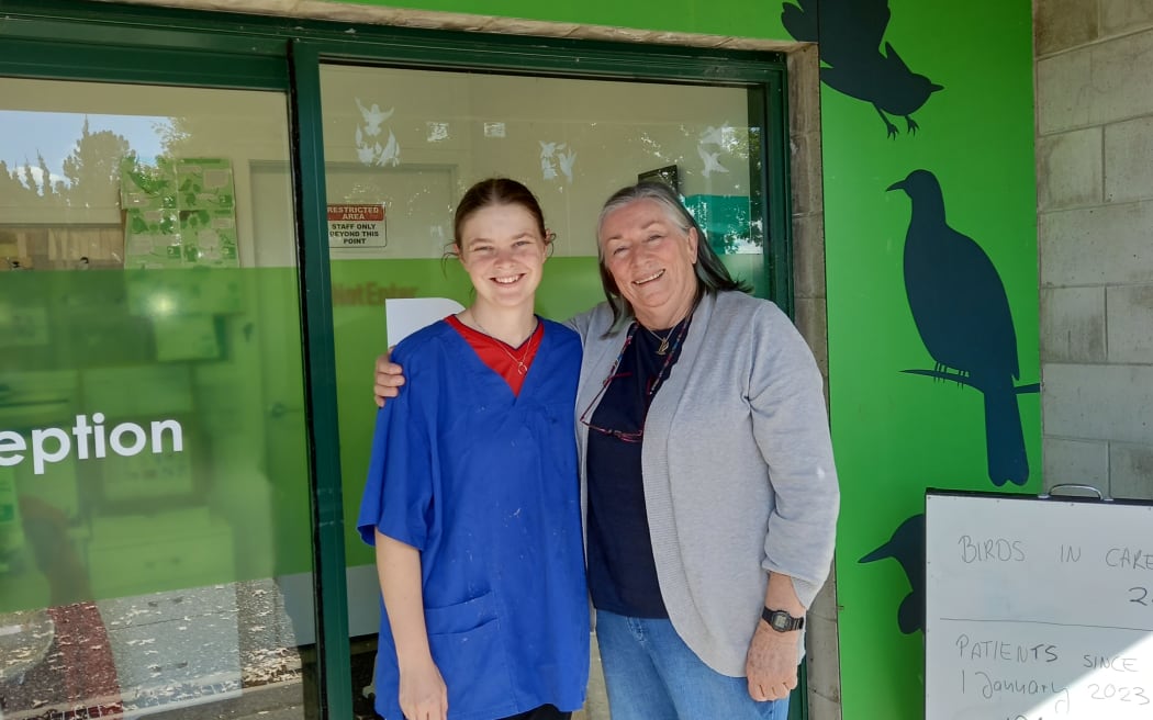 Two women standing out the front of Birdcare reception. They are smiling and one is wearing blue scrubs.
