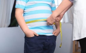 A doctor measuring a boy's waist.
