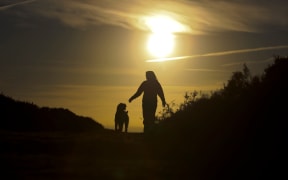 Woman walking her dog at Sunset
