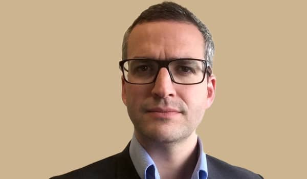 Dr James Kinross is a serious looking man with cropped greying hair and dark-rimmed glasses.