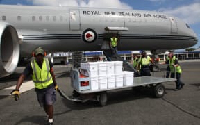 A baggage handler at Bauerfield Airport, Port Vila, Vanuatu, pulls a trolley containing water containers from a Boeing 757 to a waiting RNZAF C130 Hercules. The Boeing arrived at Port Vila with 11 tonnes of relief supplies for Ambae Island.