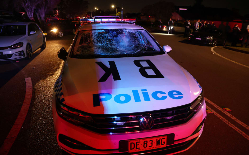 A damaged police car is seen after a mob was pushed back by police outside the Christ the Good Shepherd Church in Sydney's western suburb of Wakeley on April 15, 2024, after several people were stabbed in the church premises. Australian police arrested a man after several people were stabbed at a church in Sydney on April 15 and emergency services said four people were being treated for non-life threatening injuries. (Photo by DAVID GRAY / AFP)