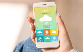 Young woman using weather forecast app in her mobile phone, closeup