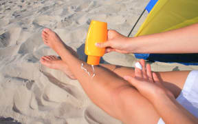 Beautiful woman putting the cream on her legs
