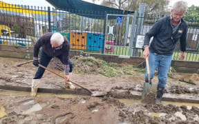 Work to clear mud and debris from Conway Street in Macandrew Bay behind the local school. A resident says a flood barrier helped to protect the school from damage.