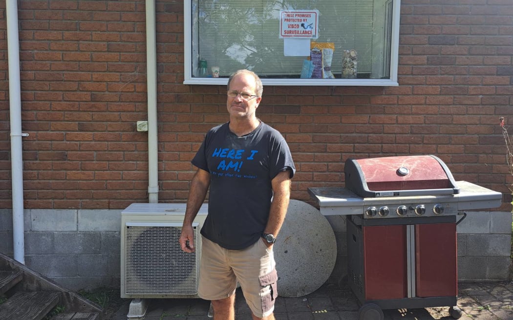 Glenn Whittington stands outside his partner's flood-damaged property.