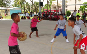 Elementary age students in Majuro competing in a basketball game.