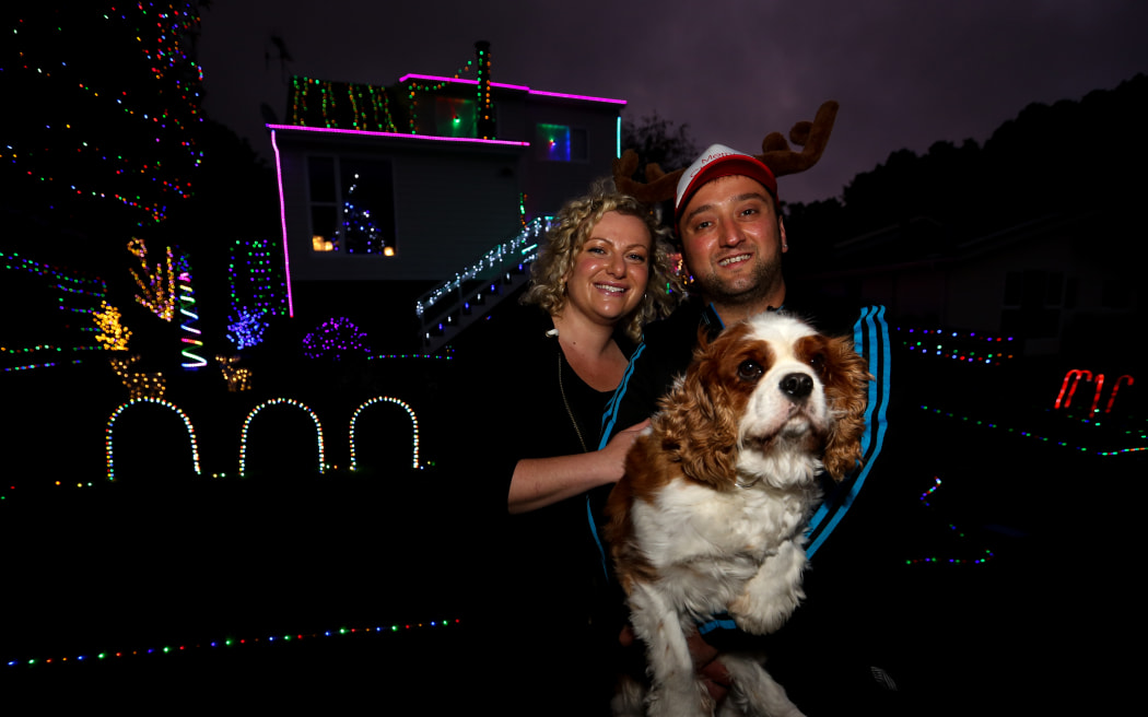 Laura and Sargoon Yousif with their dog, Ollie, outside their festive home.