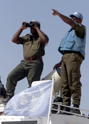 A Fijian UN peacekeeper looks through binoculars at an Israeli post from the Al-Labbouneh hill near Naqoura on the Mediterranean coast 30 July 2000 where fifty Fijian troops took up position.