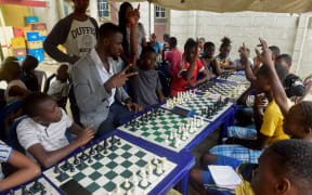 Chess consultant and player Tunde Onakoya (C/L) gestures as he addresses children during a chess class at Ogolonto in Ikorodu district of Lagos on August 17, 2019. In front of chess boards in Lagos, children are busy, concentrating. They are thinking about the next move they will make, as part of a project that is supposed to bring hope to a slum in Nigeria's megapolis. While dozens of matches are played simultaneously, participants, some as young as three years old, practice this brain game often considered out of reach for the poor populations of Africa's most populous country. (Photo by PIUS UTOMI EKPEI / AFP)